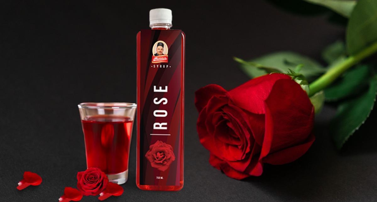 A bottle of Bhikkilal’s Rose Syrup with fresh rose petals, showcasing its rich color and natural ingredients